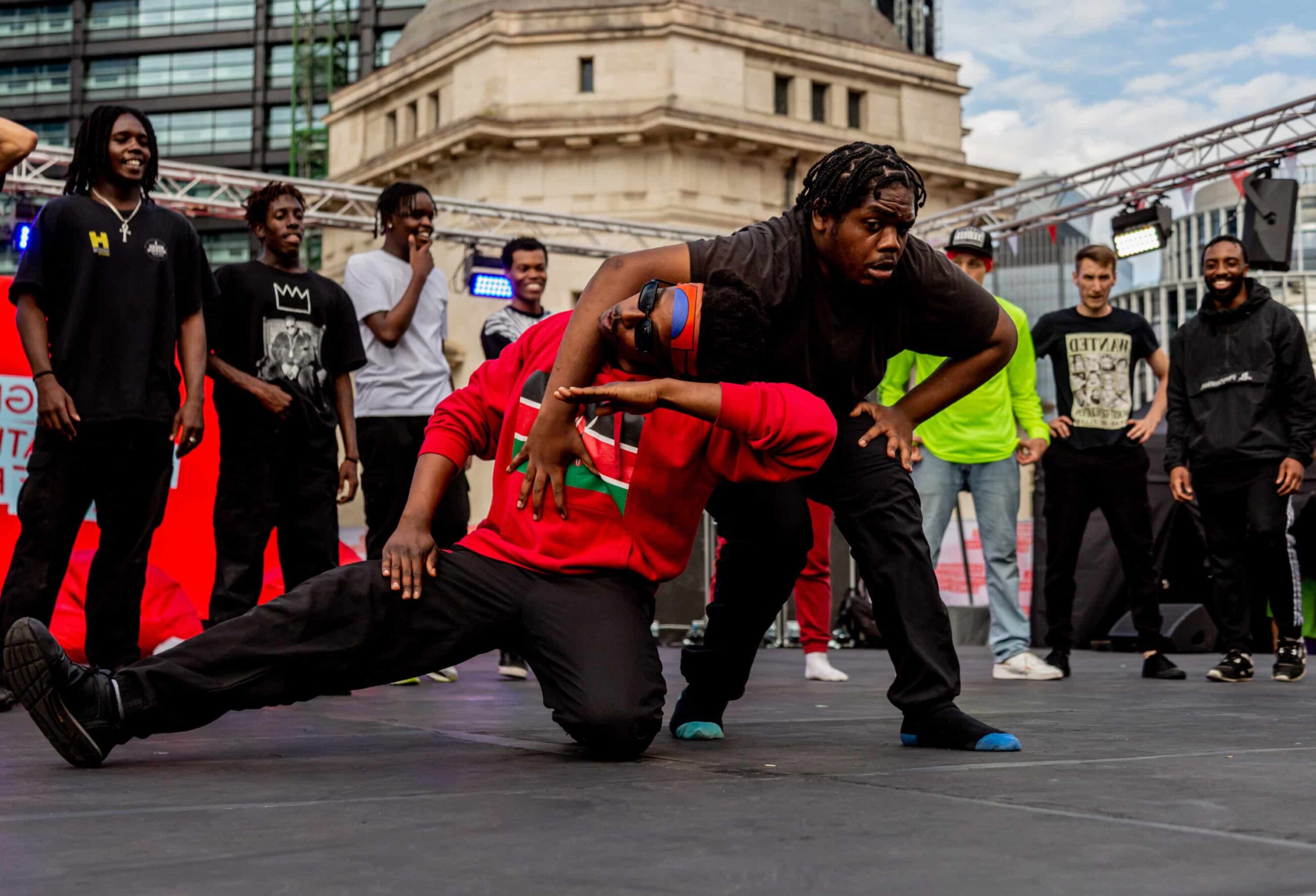 Two dancers battle in the middle of a circle of people in an outdoor space.