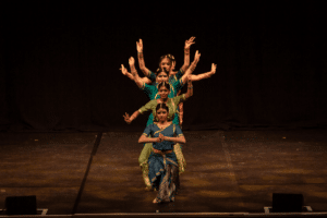 Performers in a line create a shape with their hands.