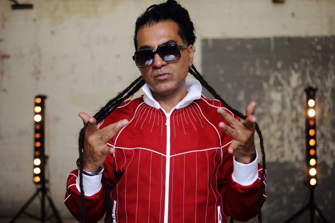 Apache Indian poses against a wall.