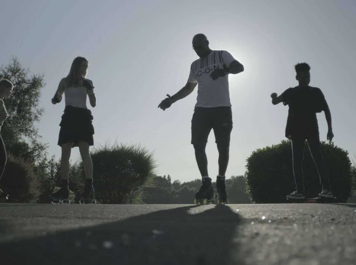 Four people rollerskate on a street.